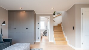 A modern living room with a grey sofa, a large grey wardrobe, and a staircase leading to another room. - F'27 Living, Whg. 06 - F27 Living (Sylt)