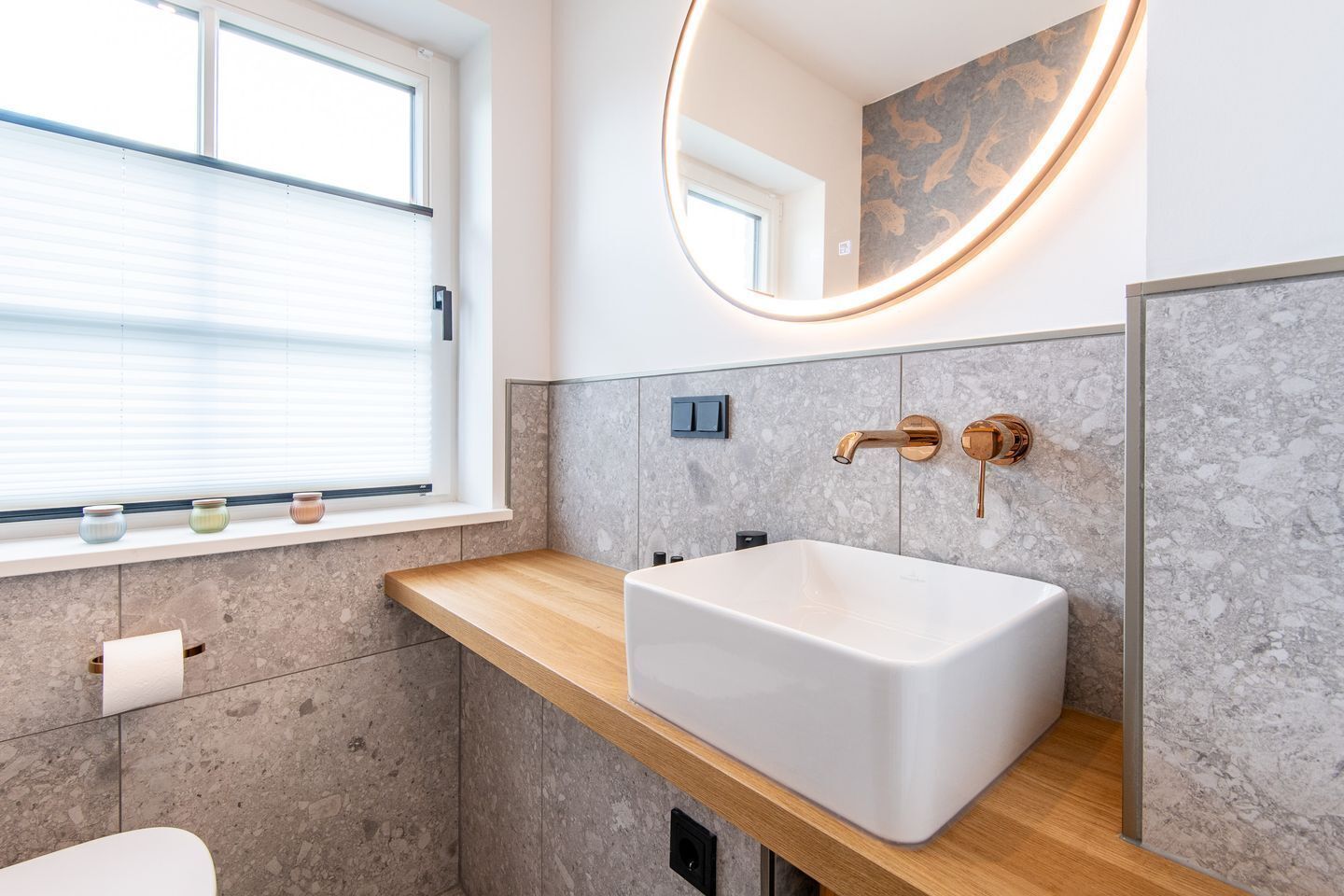 Un baño moderno con un lavamanos grande y rectangular, una encimera de madera, una ventana con persianas y un espejo instalado en la pared.