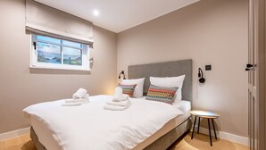 Een moderne slaapkamer met een groot bed, twee kussens, een nachtkastje en een raam met uitzicht.