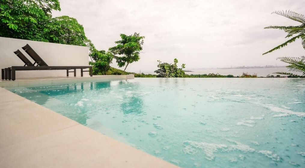 A swimming pool with lounge chairs and a view of the sea.