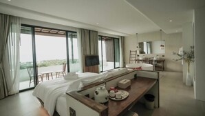 A modern hotel room with a large bed, a dining area, and a balcony with a view. - Pichcha Kohlarn (Koh Lan)
