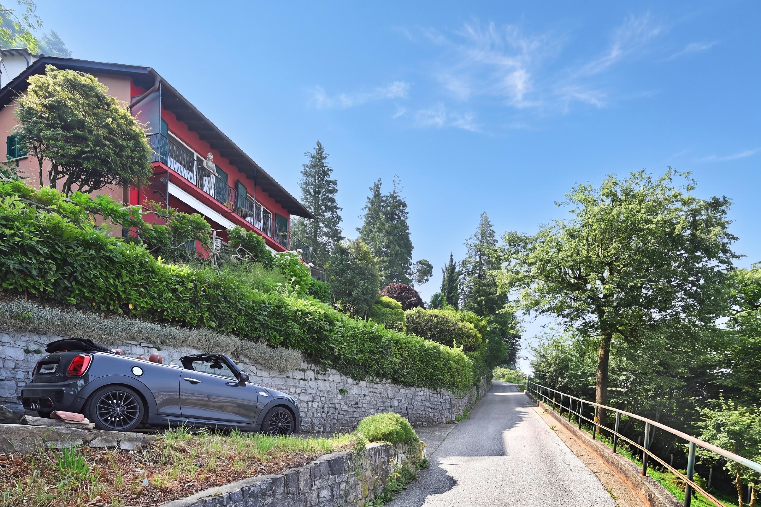 A road leading to a red building with a car parked in front.