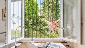 A room with a large window, a desk with a book, a hat, a lamp, and a decorative star. - Family Villa - Casa Nido - Panoramica (Lugano)
