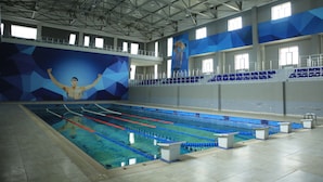 Una piscina al coperto con diverse corsie, una piattaforma da tuffo e un grande murale sulla parete.