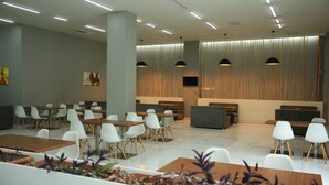 Un ristorante moderno con sedie bianche, tavoli in legno e illuminazione a sospensione.