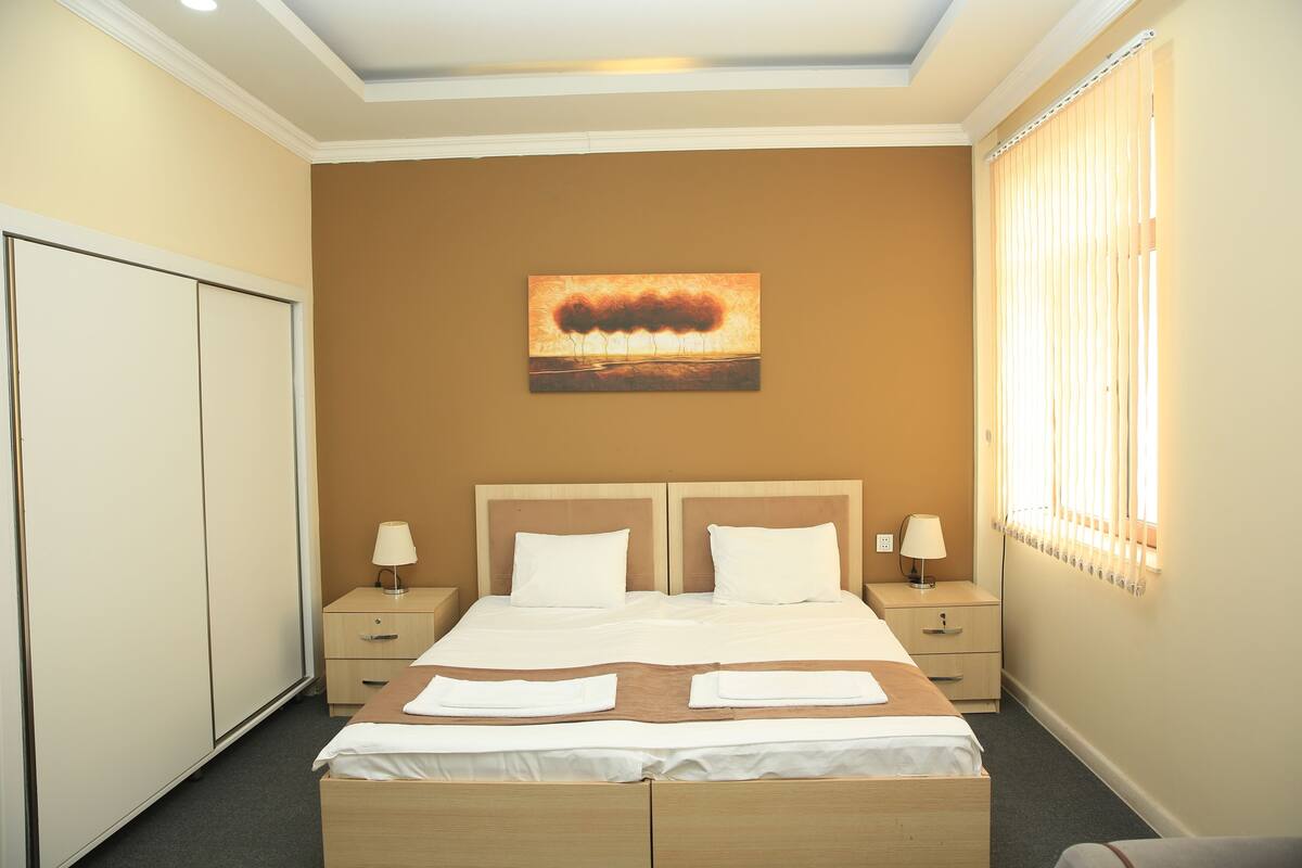 Une chambre d’hôtel avec un grand lit, deux tables de chevet avec des lampes, une armoire et un tableau au mur.