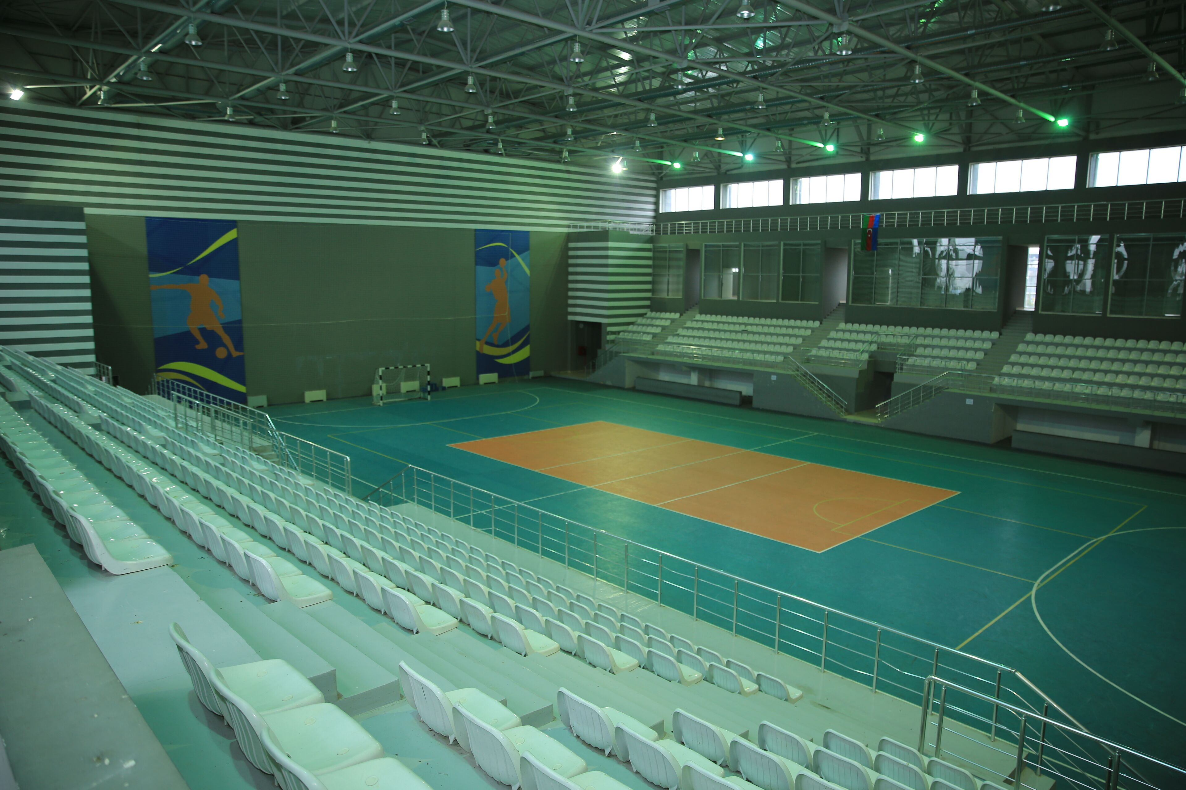 An indoor sports hall with multiple seating areas and a basketball court.