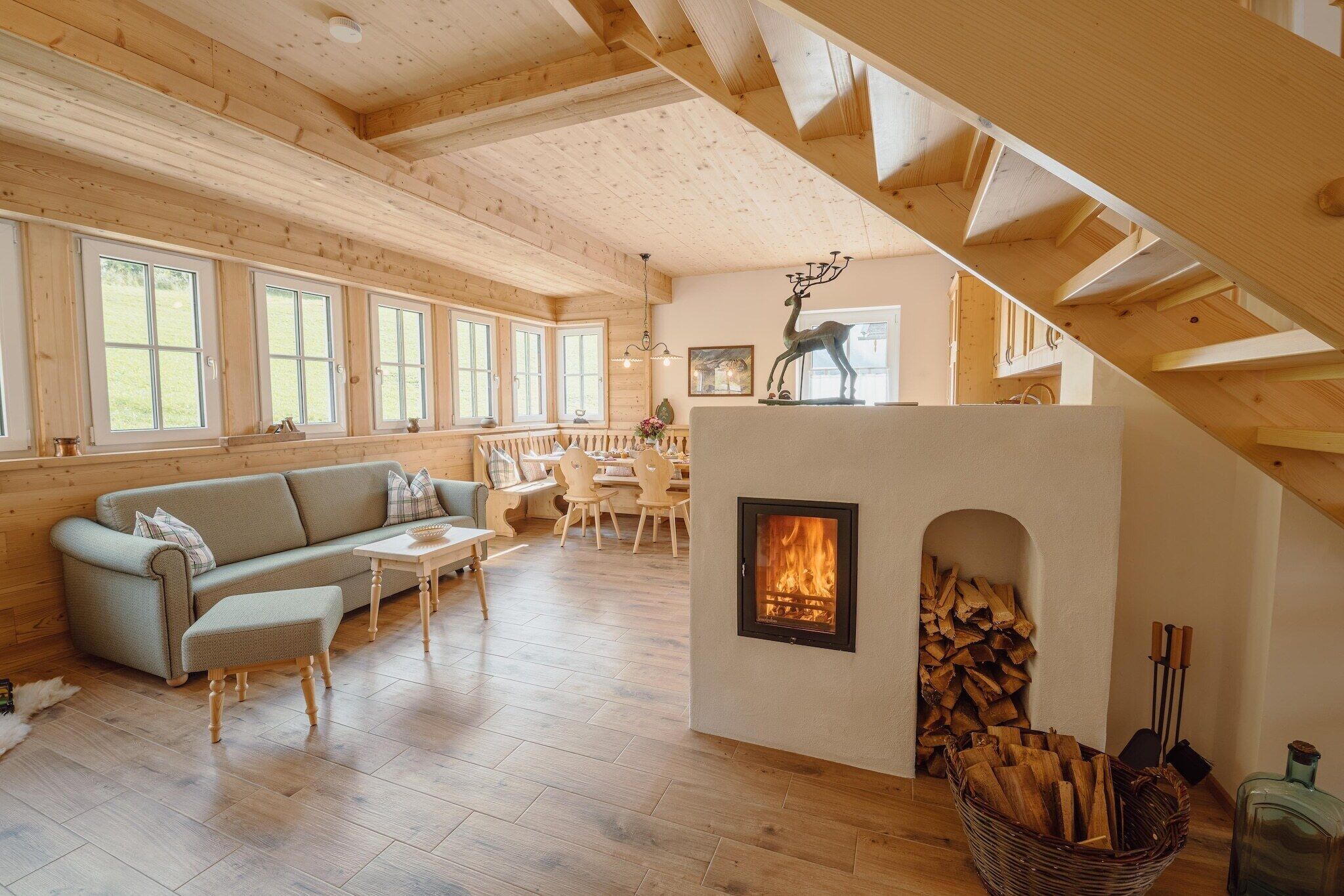 A cozy log cabin interior with a fireplace, wooden floors, a sofa, and a dining area.