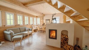 Ein gemütliches Blockhaus-Interieur mit Kamin, Holzböden, einer Couch und einem Essbereich.