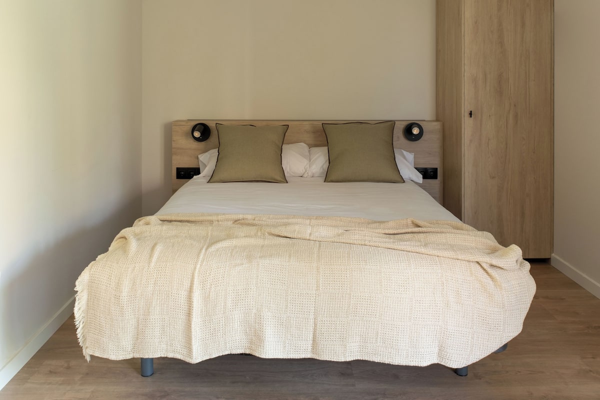 A bedroom with a bed, wooden headboard, and a wardrobe.