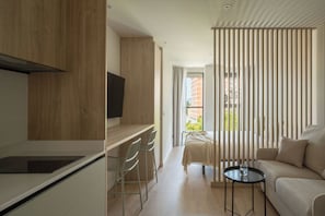 A modern, compact room with a kitchenette, a sofa, a small table, and a balcony with a view. - Líbere Pamplona Universidad (Pamplona)