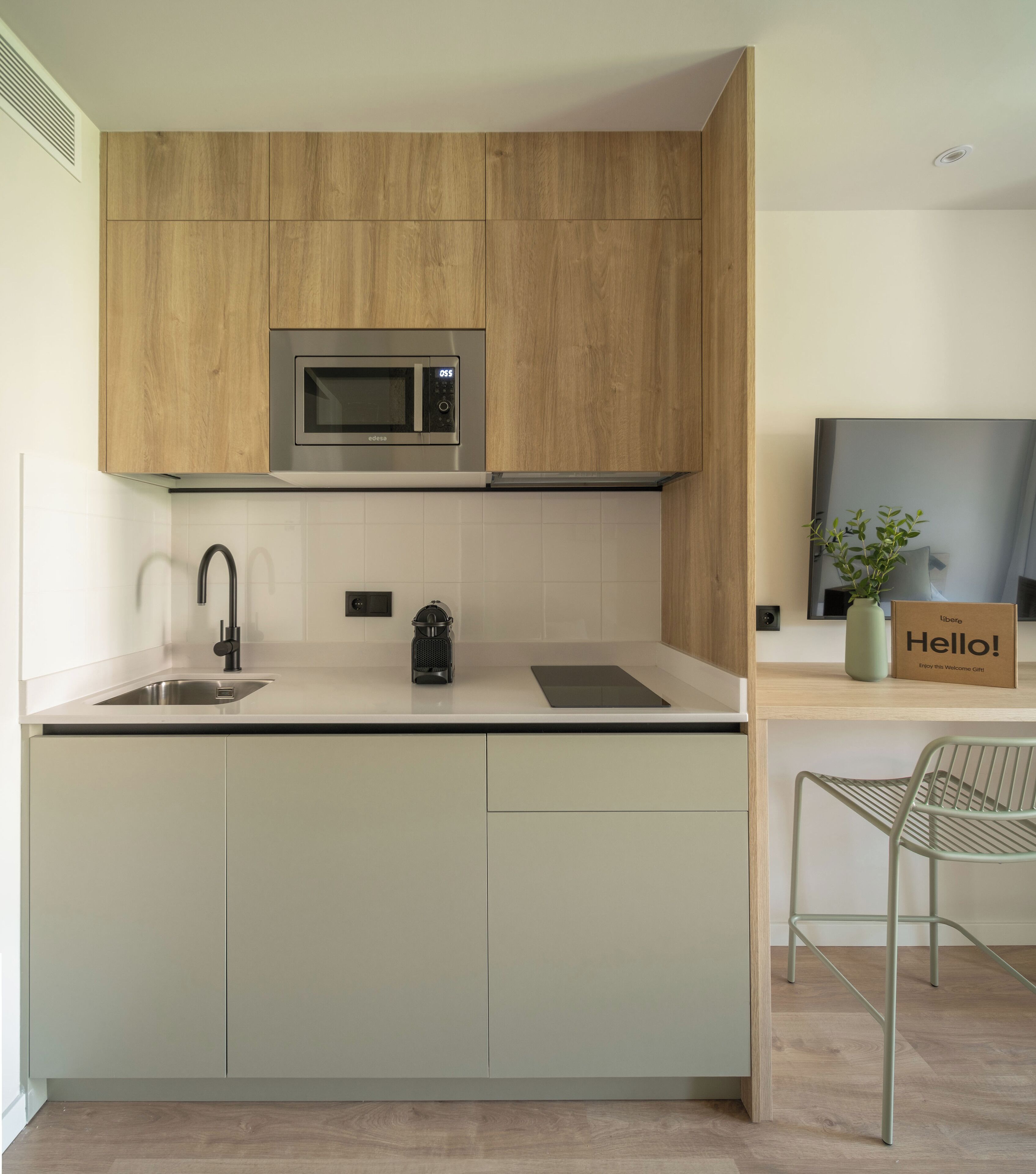 Een moderne keuken met een ingebouwde magnetron, een roestvrijstalen spoelbak en een waterkoker.