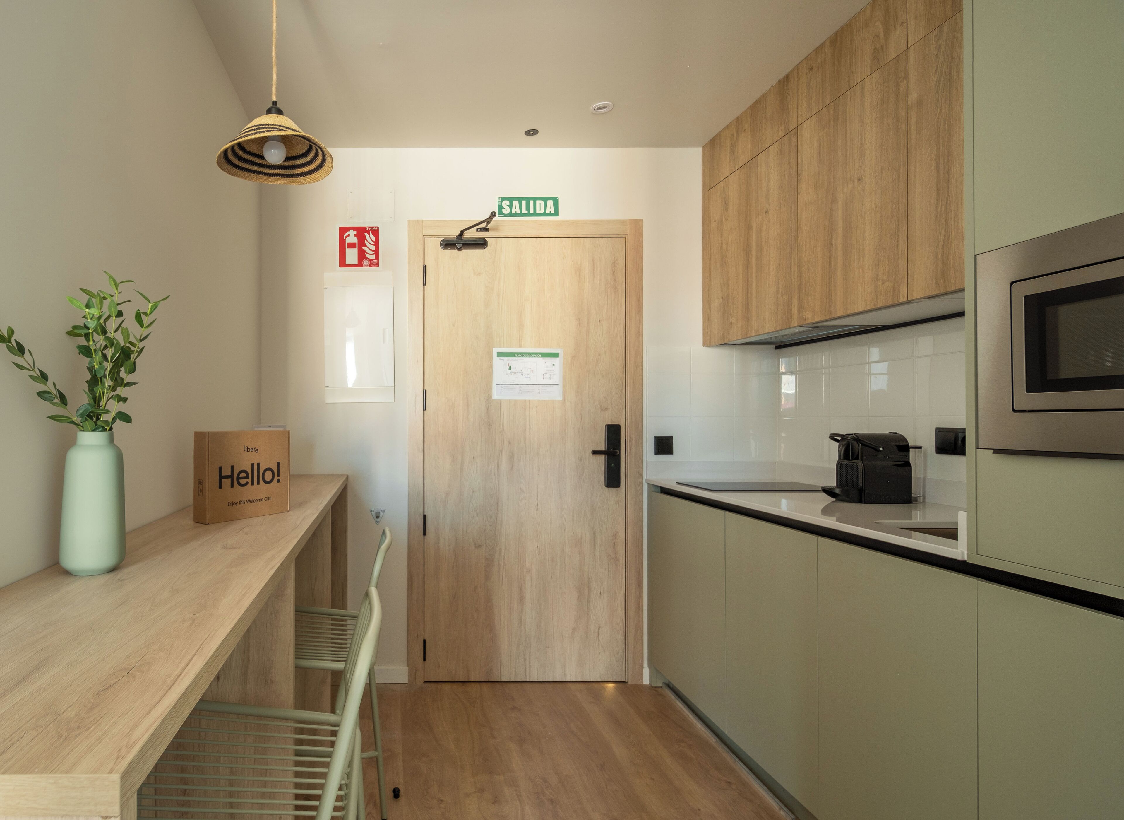 A modern kitchen with wooden cabinets, a microwave, and a 'SALIDA' sign above the door.