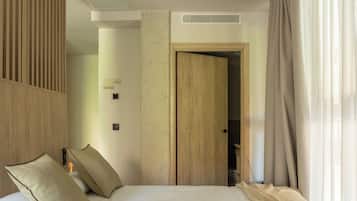 Ett modernt hotellrum med en stor säng, träpanel på väggarna, en trädörr och utsikt över korridoren.