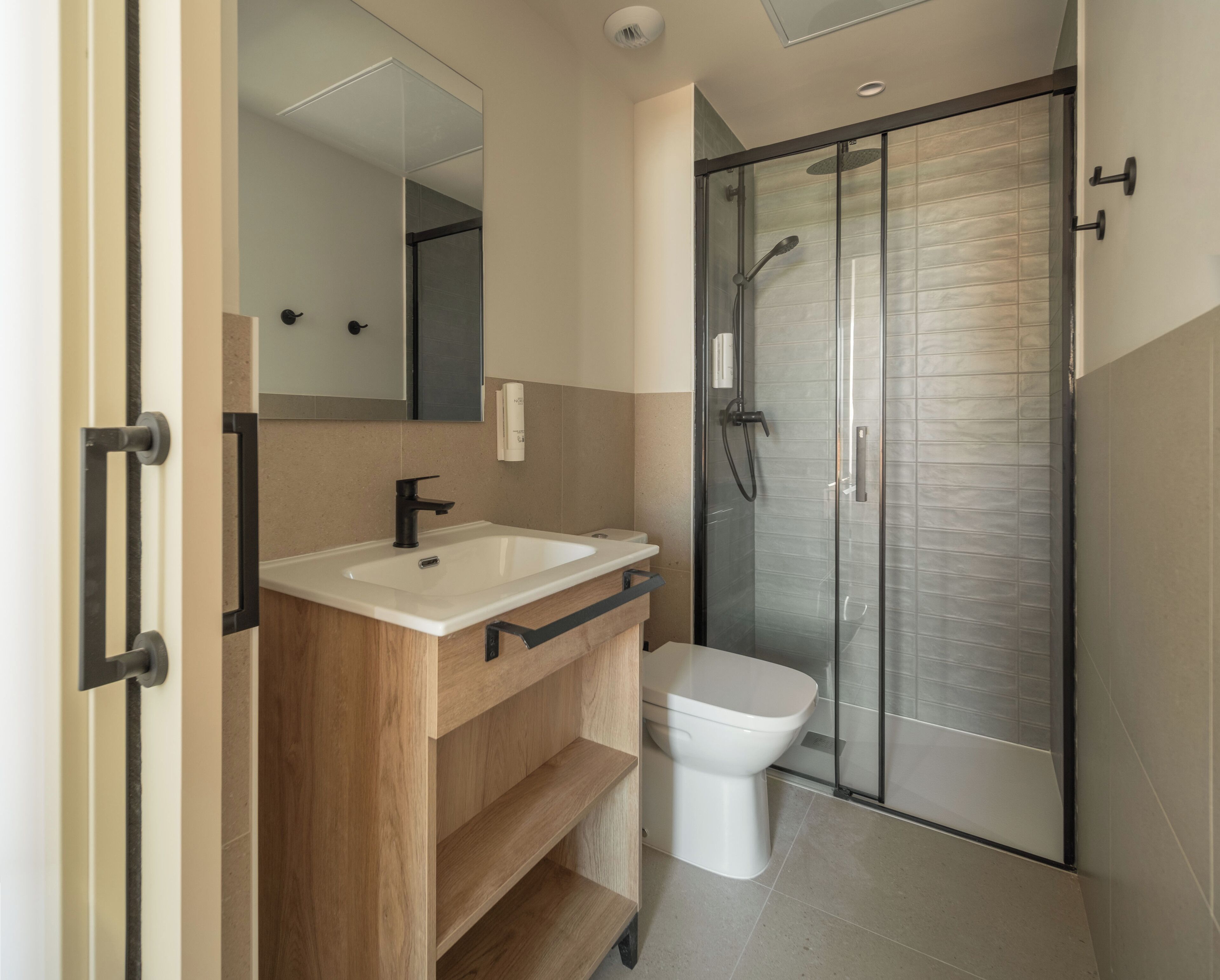 A modern bathroom with a glass-enclosed shower, a white sink, and a wooden vanity.