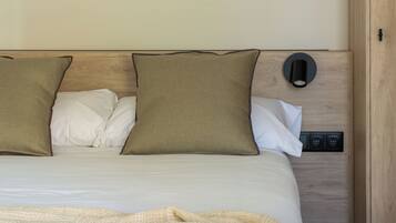 Een net opgemaakt bed met een beige deken, twee kussens en een bedpaneel.