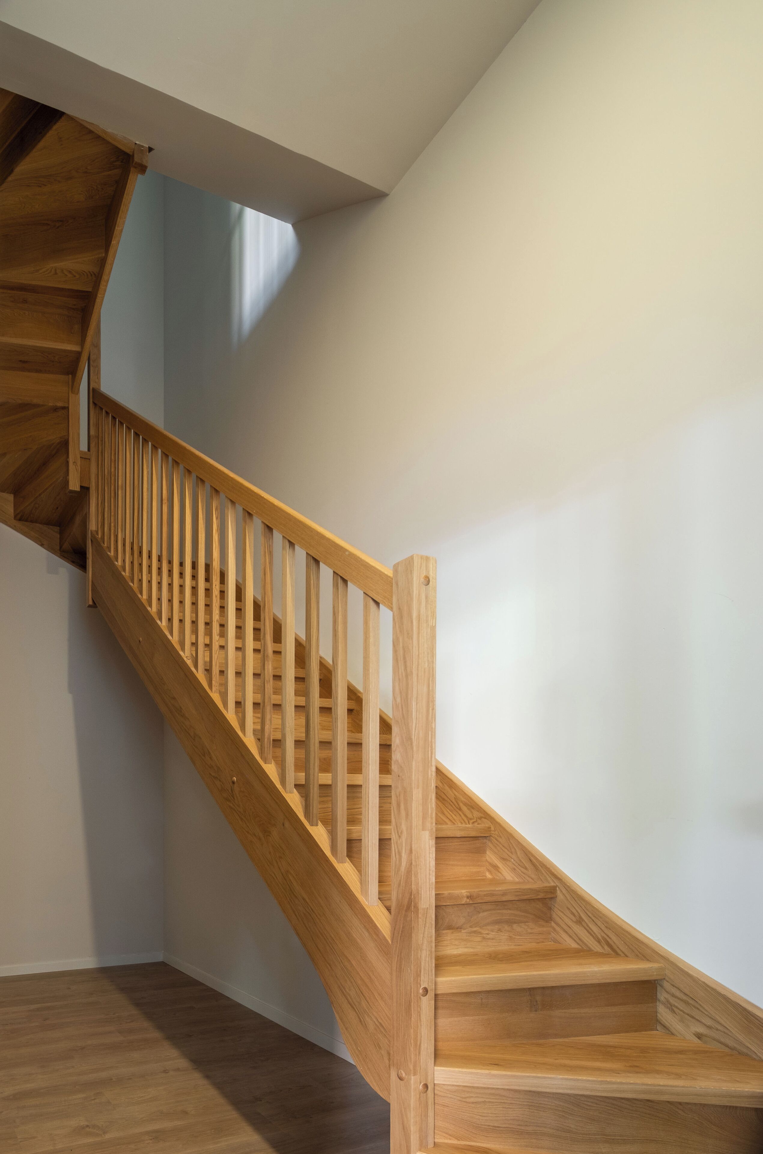 A wooden staircase with a handrail, leading to an upper floor.