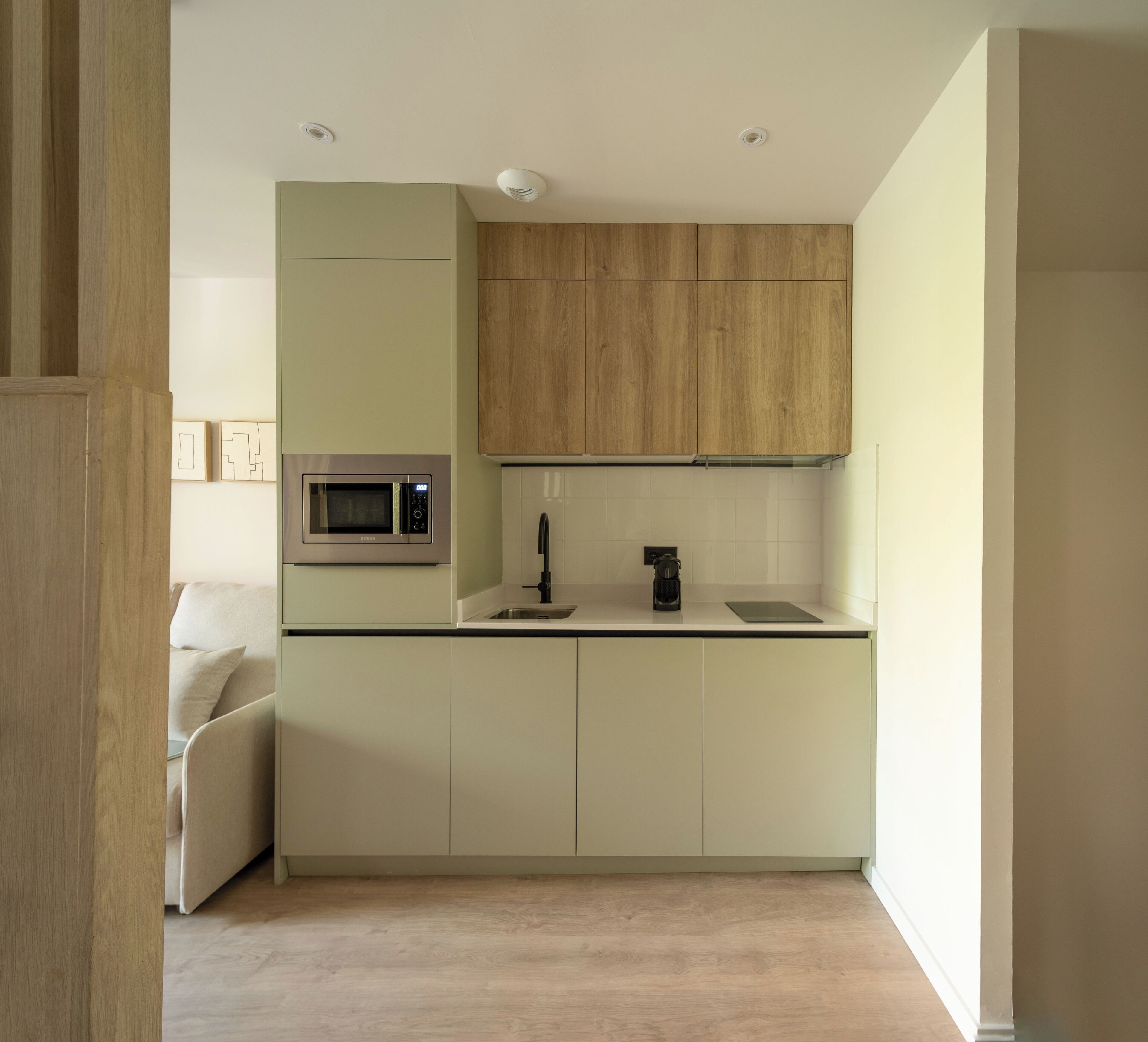 Una cocina moderna con microondas integrado, cafetera y lavamanos.