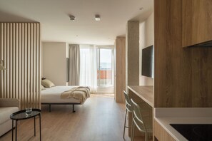 Une chambre d’hôtel moderne équipée d’un lit, d’un bureau, d’une chaise, d’une télévision et offrant une vue sur l’extérieur.