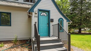 A house with a blue door, number 1616, and a small porch with steps and a railing. - Quintessential University District Home (Missoula)