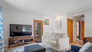 A living room with a flat-screen TV, a sofa, a coffee table, and a bookshelf. - Quintessential University District Home (Missoula)