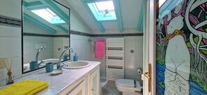 Une salle de bain avec un puits de lumière, un lavabo, un miroir, des toilettes et un porte-serviettes.