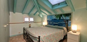 Une chambre à coucher comprenant un lit, deux lampes de chevet, une table de nuit, une fenêtre avec des rideaux et une fresque murale représentant une scène de plage.