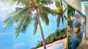 A hallway with a mural of a beach scene, including palm trees and a clear sky. - Terrazza sul Mare - by BelcantoVillas (Lido Di Camaiore)