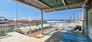 Un espace extérieur abrité, avec vue sur la mer, comprenant une piscine, des chaises et une table.
