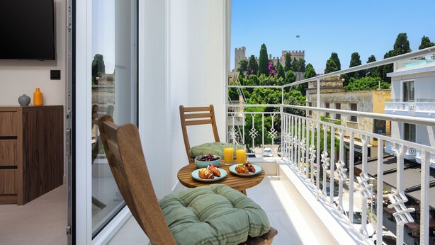 A balcony with a table set for breakfast, a chair, and a TV mounted on the wall.