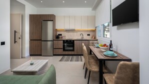 A modern kitchen with a built-in oven, a dining area with a table and chairs, and a flat-screen TV mounted on the wall.