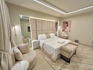 A modern bedroom with a large bed, bedside tables, a sofa, and a small table.