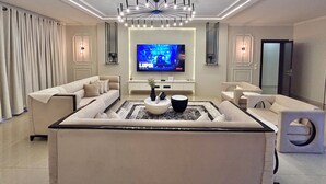 Un soggiorno moderno con TV a schermo piatto, divano, tavolino e lampadario.