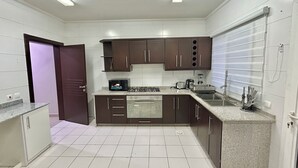 Una cucina moderna con pavimento piastrellato in bianco, mobili scuri in marrone e elettrodomestici in acciaio inossidabile.
