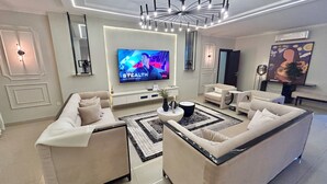 Un soggiorno moderno con una grande TV a schermo piatto, un lampadario e un divano.