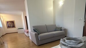 A modern living room with a grey sofa, a white coffee table, and a wooden floor.