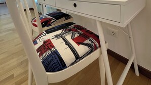 A white desk with a chair that has a patterned cushion.
