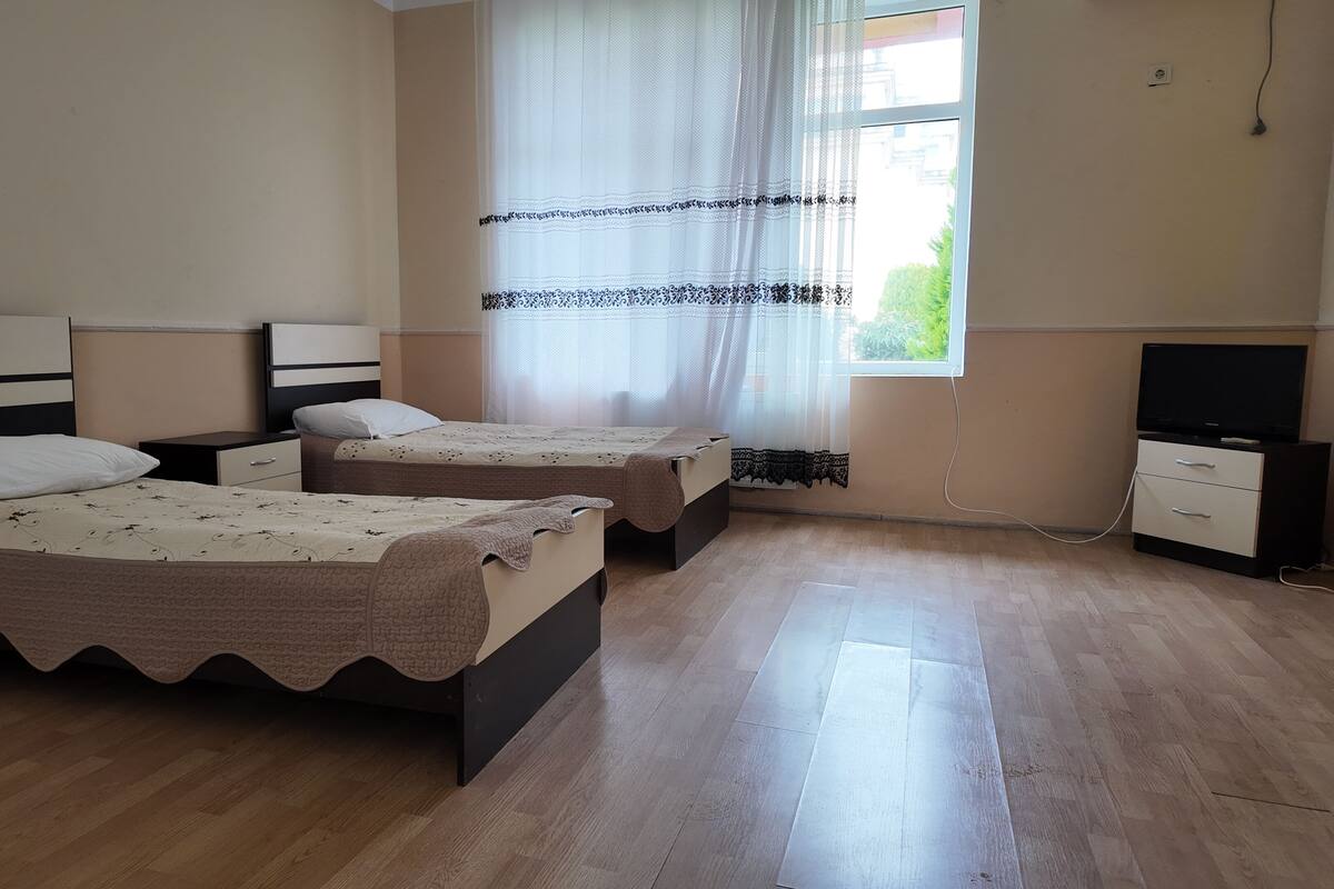A room with two beds, a TV, and a window with curtains.