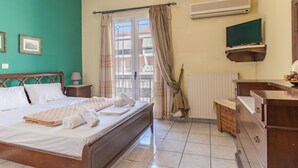 Et hotelværelse med en seng, en trækommode, et fjernsyn og et vindue med gardiner.
