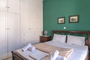 Una habitación de hotel con cama, armario, mesita de noche y dos cuadros en la pared.