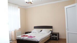 A bedroom with a bed, nightstands, a wardrobe, and a radiator.