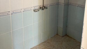 A bathroom with a shower, tiled walls, and a tiled floor.