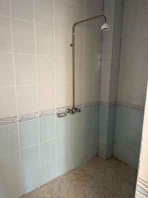A bathroom with a shower, tiled walls, and a tiled floor.