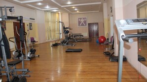 Een fitnessruimte met diverse trainingsapparaten, waaronder loopbanden, hometrainers en krachtapparaten.