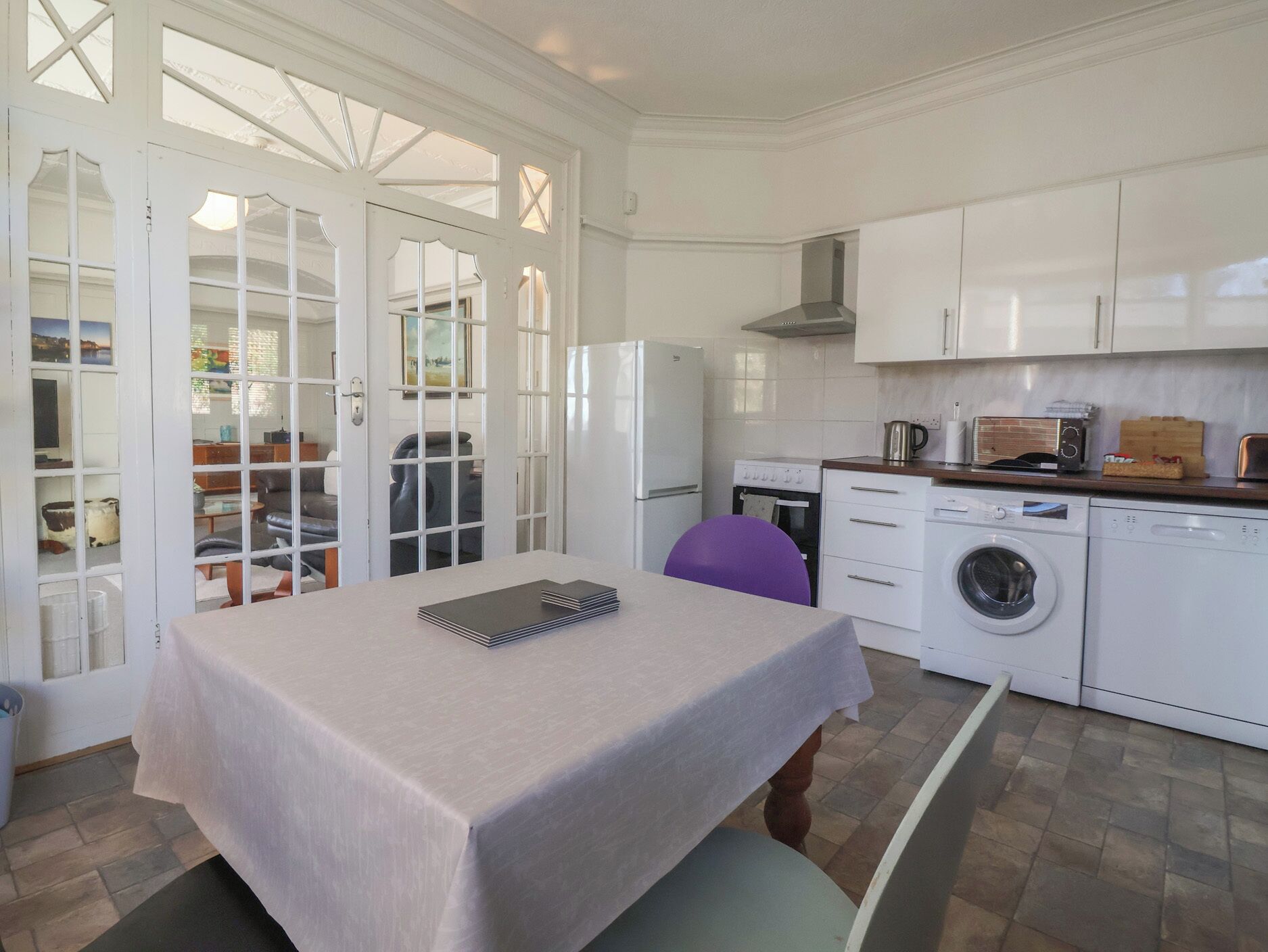 A compact kitchen with a dining table, a washing machine, and a microwave.