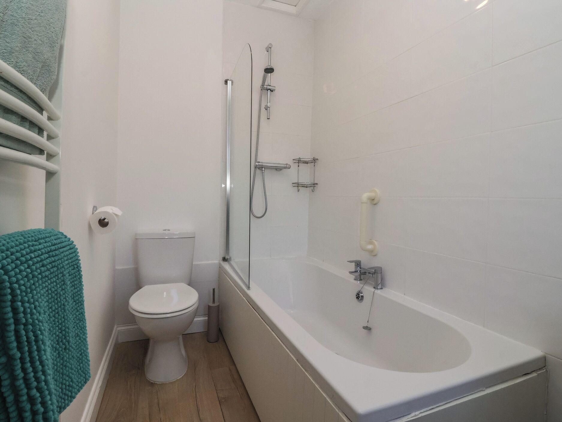 Un baño con inodoro, ducha con puerta de vidrio y bañera.