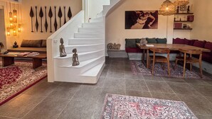 Ein modernes Wohnzimmer mit weißer Treppe, einem Essbereich mit Holzmöbeln und Dekoration an den Wänden.