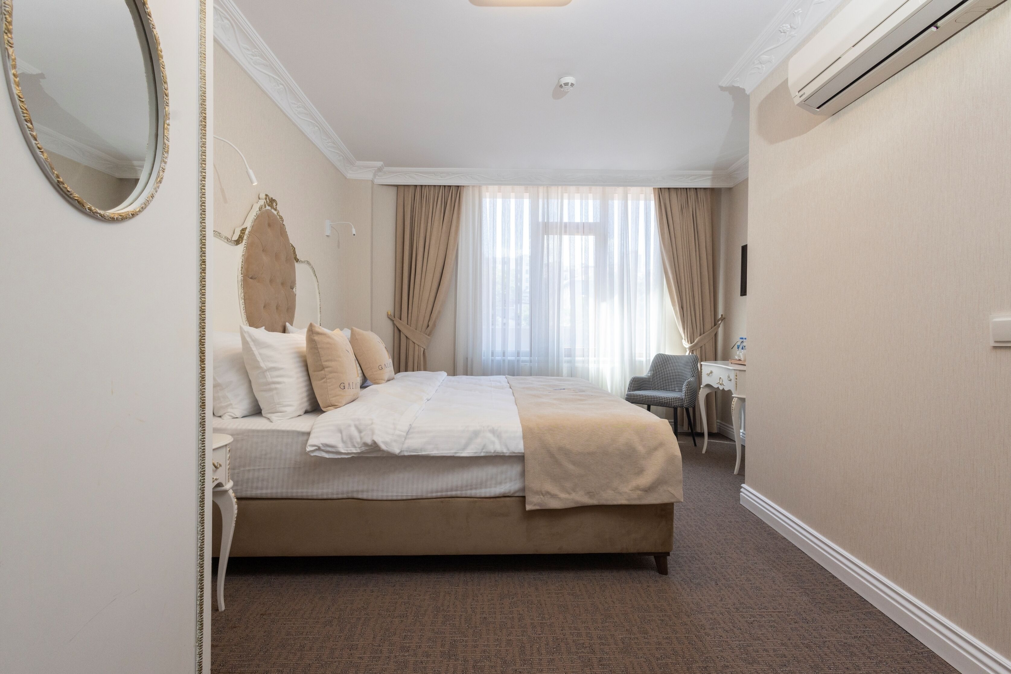 A hotel room with a large bed, a desk, and a chair.