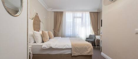 A hotel room with a large bed, a desk, and a chair.