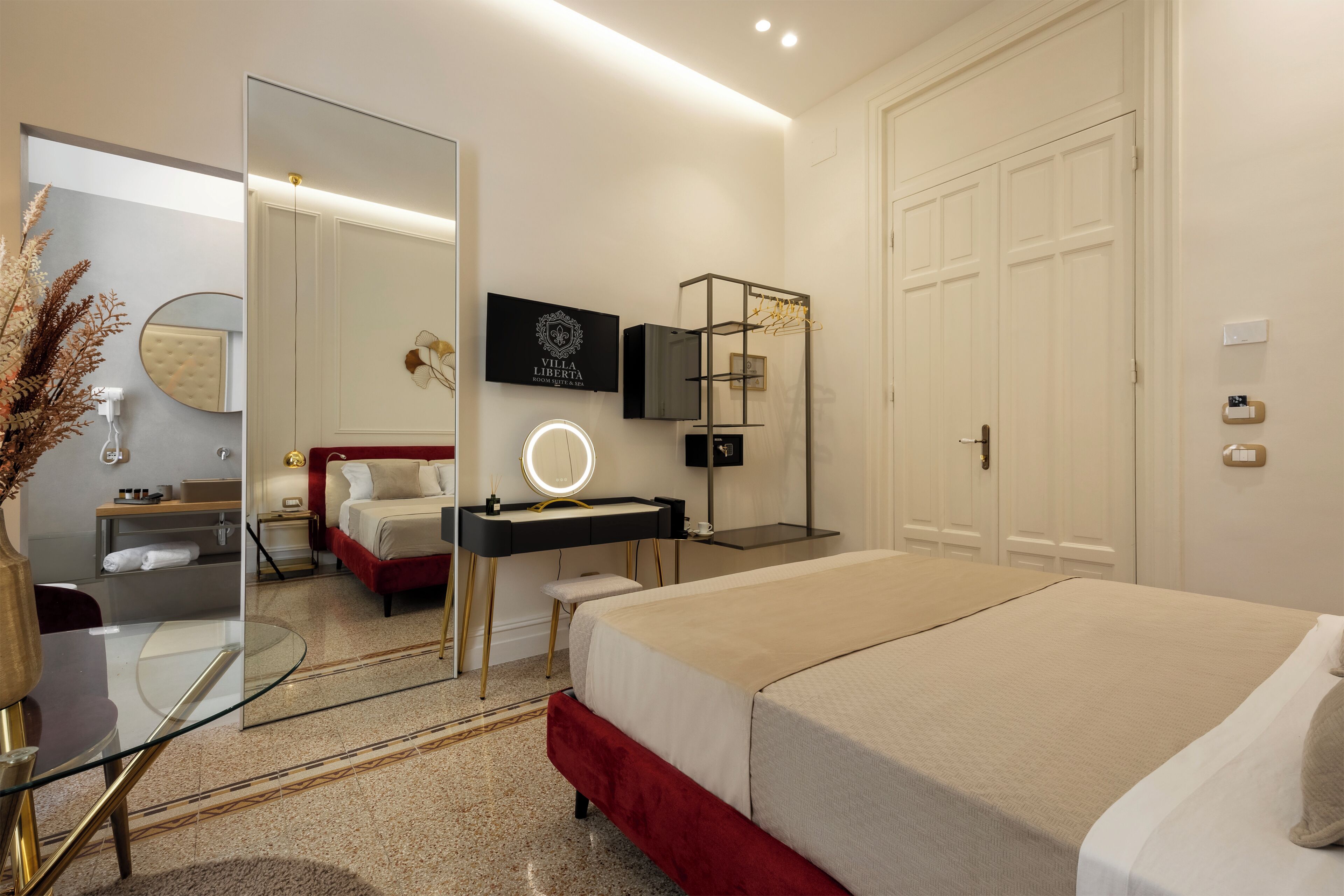 Une chambre d’hôtel moderne équipée d’un grand lit, d’une coiffeuse avec miroir, d’une télévision et d’une armoire.
